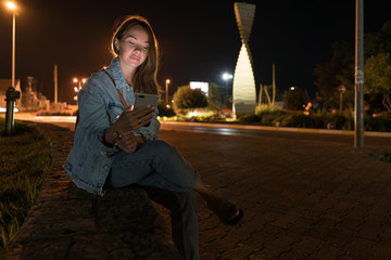 Young woman using mobile phone on street at night