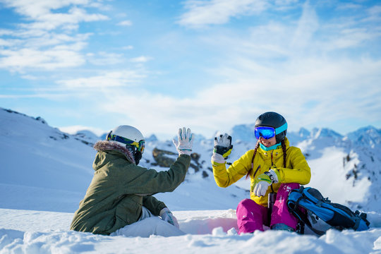 Photo of two tourists doing handshake sitting on snow resort .