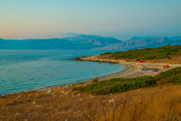 Sunset at Antinioti West Beach in Corfu Island. Tourists are relaxing in background