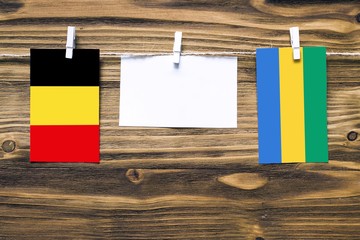 Hanging flags of Belgium and Gabon attached to rope with clothes pins with copy space on white note...
