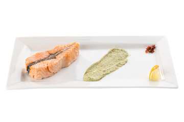 Steamed salmon fillet with lemon and guacamole on white plate isolated on white background
