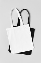 White and black tote bags mockup on a grey background.
