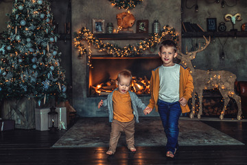Two boys, two brothers play under the Christmas tree in the New Year.