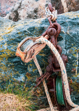 Rusty chain on green rock with pulley