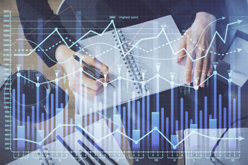 Forex chart hologram on hand taking notes background. Concept of analysis. Multi exposure