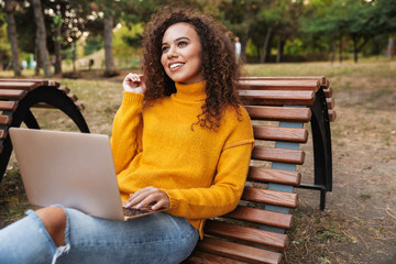 Obraz premium Happy beautiful young curly woman using laptop computer.