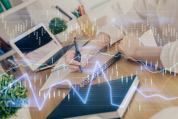 Financial graph displayed on woman's hand taking notes background. Concept of research. Double exposure