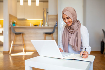 Pretty woman wearing hijab in front of laptop search and doing office work with different face...