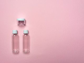 Travel set of bottles and jars on a pink background