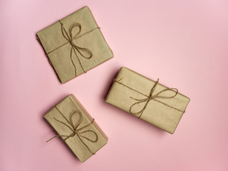 gifts wrapped in craft paper on a pink background