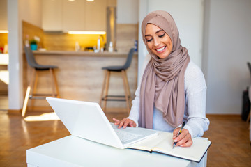 Young saudi business woman working in at home, pointing on laptop, copy space. Muslim female...