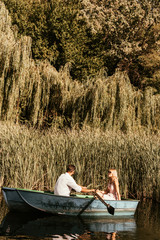 Young couple in boat on lake near thicket of sedge