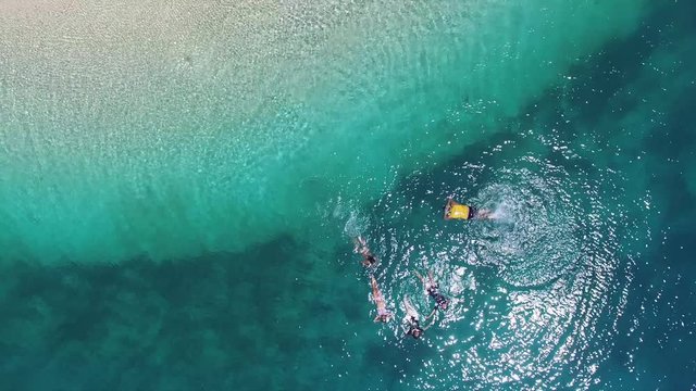 Group of coed mal and female mixed sex adventurous young professional workplace office friends swim snorkel at the edge of a sand bars deep drop