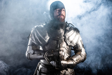 Fototapeta na wymiar handsome knight in armor looking away on black background