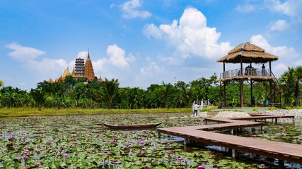 Fototapeta na wymiar Beautiful Lotus lake with wooden bridge and Wat Tham Sua temple background at Cafe Rimbua Kanchanaburi Thailand