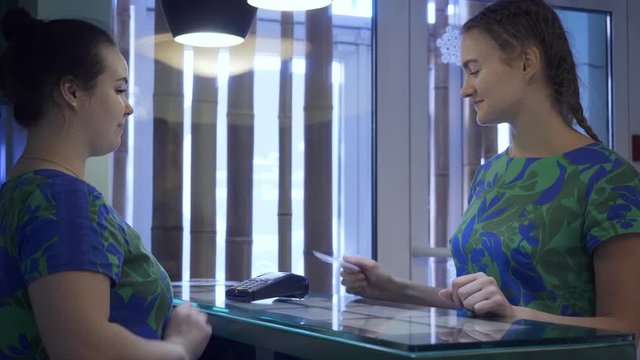 Young woman pays services with a card.