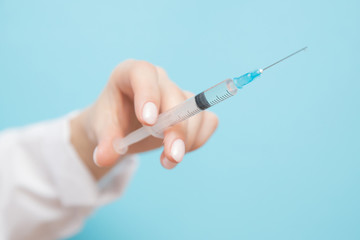 Beauty spa doctor holding syringe on blue background. Female hand with manicure