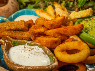 Plate with snacks for beer. French fries, cheese sticks, onion rings and white sauce