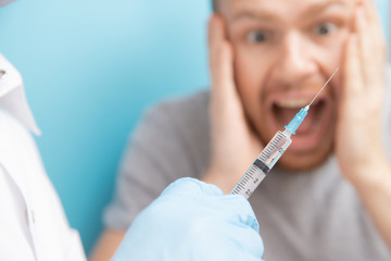 Man is fear and cries from syringe with vaccination doctor appointment. Concept trypanophobia