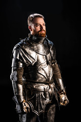 Fototapeta na wymiar handsome knight in armor looking away isolated on black