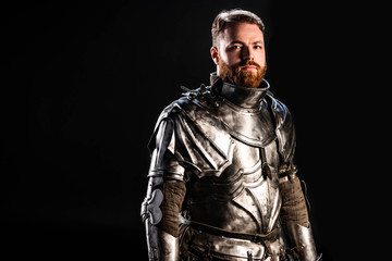handsome knight in armor looking at camera isolated on black