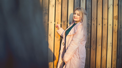 A portrait of a beautiful girl, posing near a wooden fence at sunset in springtime.