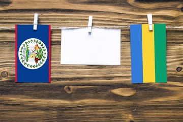 Hanging flags of Belize and Gabon attached to rope with clothes pins with copy space on white note...