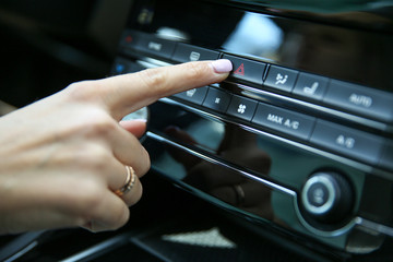 the hand of the car driver turns on the alarm. woman's hand presses the Emergency button with red triangle in the car close-up