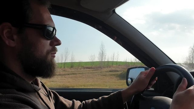 lifestyle bearded man driving a car and driving on a country highway.