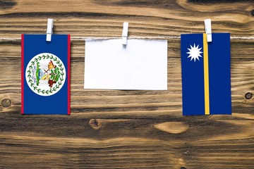 Hanging flags of Belize and Nauru attached to rope with clothes pins with copy space on white note paper on wooden background.Diplomatic relations between countries.