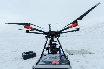 Professional video camera and modern drone in winter cold field.