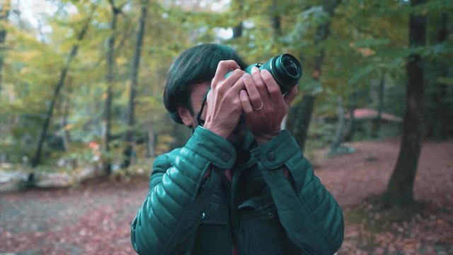 Young amateur photographer taking shot on autumn time in forest. Lifestyle concept, learning photograph in nature. Traveler concept.