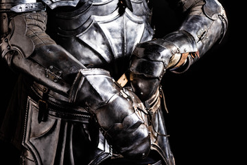 Fototapeta na wymiar cropped view of knight in armor holding sword isolated on black