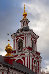 Fototapeta na wymiar The bell tower of an Orthodox church in red with a golden dome