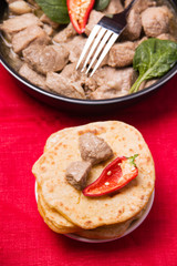 Tortilla with meat and pepper on a red textile background. Near Fajita in a pan. The ingredients