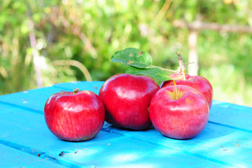 Fresh sweet ripe red apples on the blu wooden table
