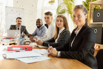 Group of young business professionals having a meeting. Diverse group of coworkers discuss new decisions, future plans and strategy. Creative meeting and workplace, business, finance, teamwork.