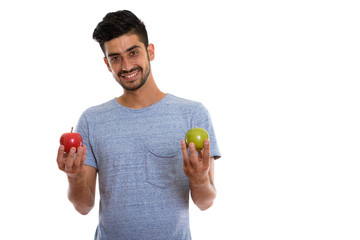 Studio shot of young Persian man holding red apple and green apple