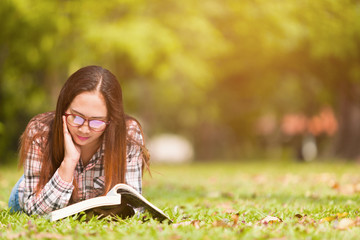Woman spend the holidays relaxing, reading books in the garden with trees and green grass. On a bright day