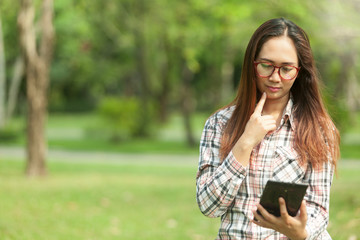 Fototapeta premium woman relaxes in the garden with reading news,check mail with a phone on a bright day