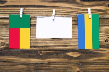 Hanging flags of Benin and Gabon attached to rope with clothes pins with copy space on white note...
