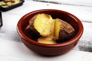 raclette cheese melting on potato served in individual skillets. swiss raclette