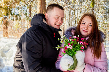 Celebration of St Valentine's day. Happy and beautiful young couple in love are walking together outdoors in winter city park, hugging each other