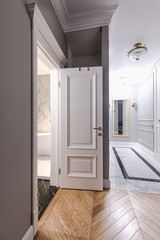 Entrance hallway in a modern apartment with a luxurious design: grey walls, built-in wardrobe, classic style