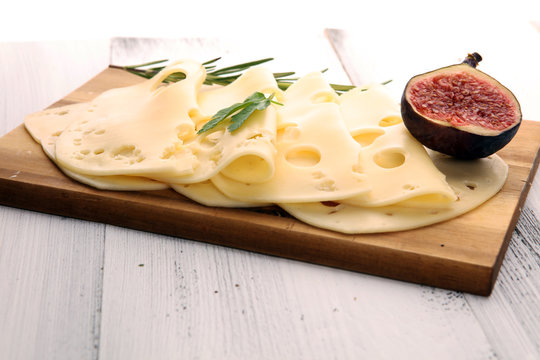 cheese slices on wooden tray with parsley. gauda cheese
