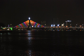 Obraz premium Han River Bridge colorfully illuminated at night and reflected in a river of Da Nang, Vietnam 