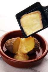raclette cheese melting on potato served in individual skillets. swiss raclette