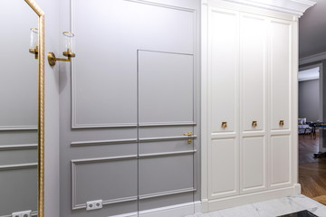 Entrance hallway in a modern apartment with a luxurious design: grey walls, built-in wardrobe, classic style