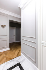 Entrance hallway in a modern apartment with a luxurious design: grey walls, built-in wardrobe, classic style