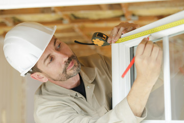 male builder measuring a window